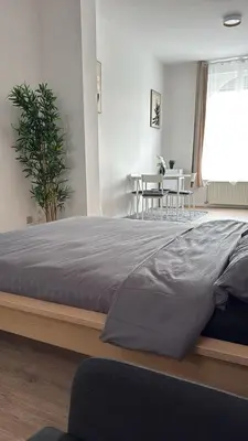 a large bed in a bedroom with a table at Studio Cosy rénové au Centre de Liège in Liège