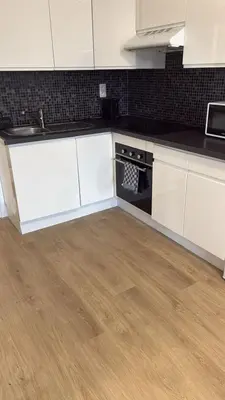 a kitchen with white cabinets and a wooden floor at Appartement fraîchement rénové de 1 chambre et Sofa Bed en plein Cœur de Liege in Liège