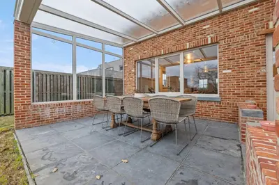 a patio with a table and chairs on a brick wall at Ruime vakantievilla in Halen voor 12 personen in Halen