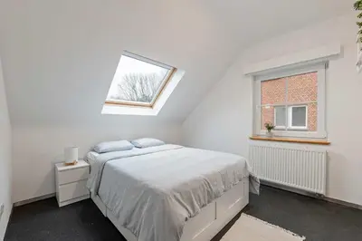 a white bedroom with a bed and a window at Ruime vakantievilla in Halen voor 12 personen in Halen