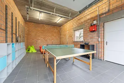 a ping pong table in a room with a brick wall at Ruime vakantievilla in Halen voor 12 personen in Halen