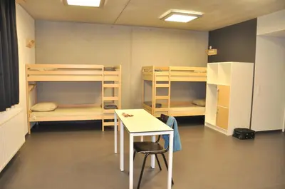 a room with bunk beds and a table and a desk at Hostel H in Hasselt