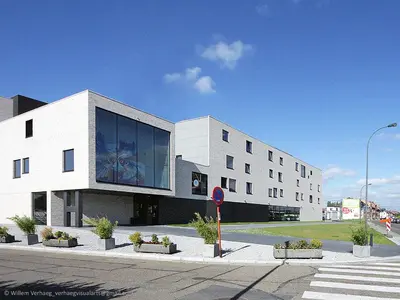 a large white building on the side of a street at Hostel H in Hasselt