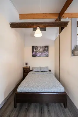 a bedroom with a bed and a wooden ceiling at DE SMISHOEVE met kinderpret, dieren en wellness in Heers