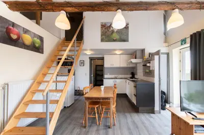 a kitchen and dining room with a staircase in a tiny house at DE SMISHOEVE met kinderpret, dieren en wellness in Heers