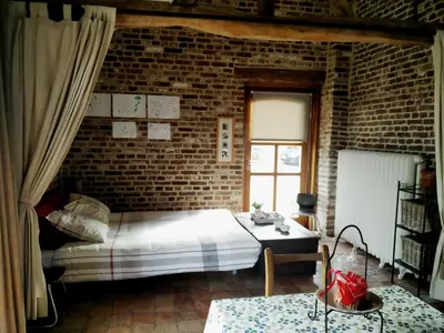 a bedroom with a bed and a brick wall at Vakantiewoning Venderhof in Maaseik