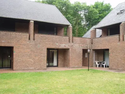a brick building with a table and chairs in a yard at Domein Hengelhoef in Houthalen-Helchteren