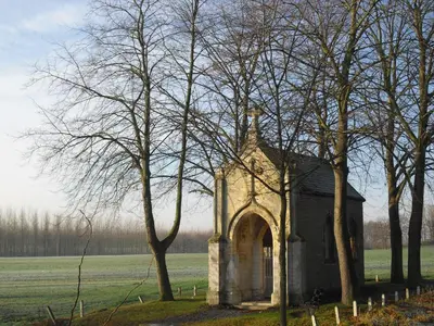 an old church in a field with trees at Kasteel Nieuwenhoven in Sint-Truiden
