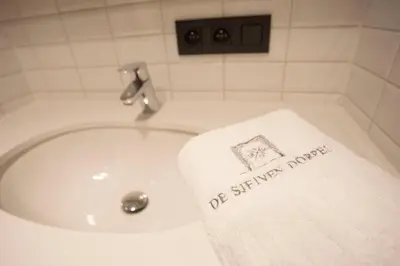 a towel on the edge of a sink in a bathroom at De Sjeiven Dorpel in Maaseik