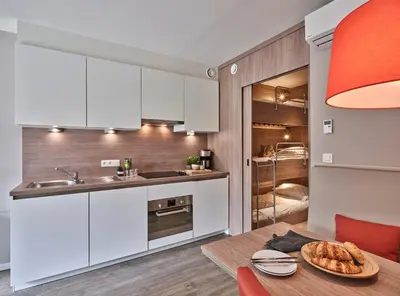 a kitchen with white cabinets and a table with a plate of bread at Green Resort Limburg in Houthalen-Helchteren