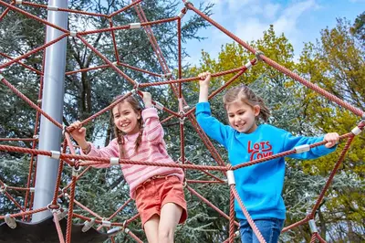 two girls playing on an obstacle course on the playground at Green Resort Limburg in Houthalen-Helchteren