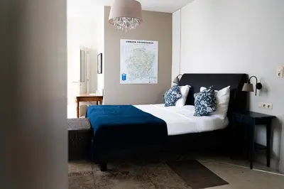 a bedroom with a blue and white bed and a chandelier at Porta Cité in Maasmechelen
