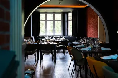 a dining room with tables and chairs and a window at Porta Cité in Maasmechelen