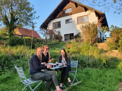 three women sitting at a table in front of a house at Villa Kakelbont Borgloon in Borgloon