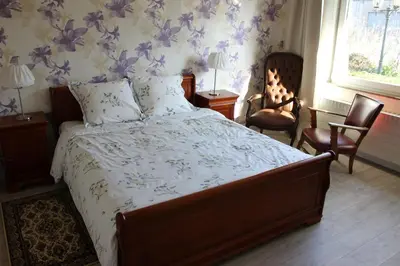 a bedroom with a bed with a floral wallpaper at Villa Kakelbont Borgloon in Borgloon