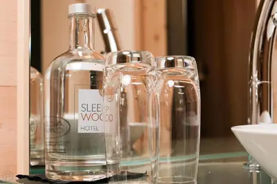 a bottle and glasses sitting on top of a counter at Sleepwood Hotel in Eupen