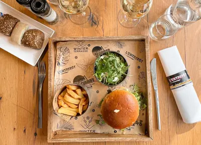 a wooden table topped with a sandwich and french fries at Hotel Verviers Van der Valk in Verviers
