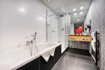 a white bathroom with a tub and a shower at Hotel Verviers Van der Valk in Verviers