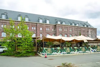 a building with a restaurant with umbrellas in front of it at Hotel Verviers Van der Valk in Verviers