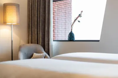 a bedroom with a bed and a chair and a window at Hotel Stayen in Sint-Truiden