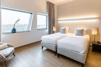 a hotel room with two beds and a chair and a window at Hotel Stayen in Sint-Truiden