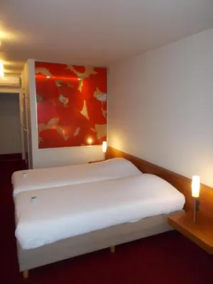 a white bed in a room with a painting on the wall at Hotel Corbie Lommel in Lommel