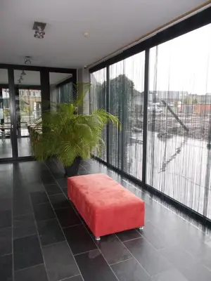 a red ottoman in a room with a large window at Hotel Corbie Lommel in Lommel