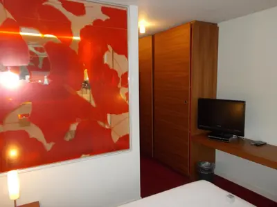 a room with a bed and a tv and a cabinet at Hotel Corbie Lommel in Lommel