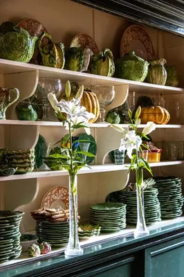 a shelf full of plates and vases with flowers in them at B&B Kasteelhoeve de Kerckhem in Wijer