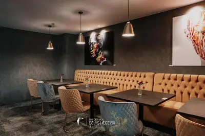 a restaurant with tables and chairs and a bench at Van Der Valk Sélys Liège Hotel & Spa in Liège