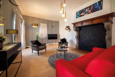 a living room with a red couch and a fireplace at Van Der Valk Sélys Liège Hotel & Spa in Liège