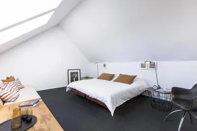 a white bedroom with a bed and a chair at côté verger B&B in Battice