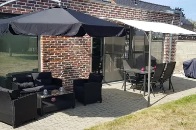 a patio with an umbrella and a table and chairs at La renaissance in Villers-lʼÉvêque