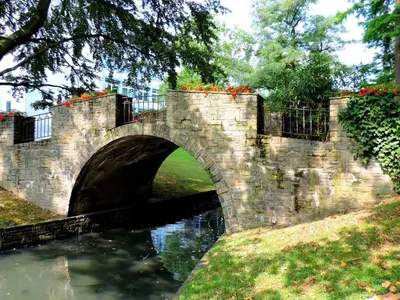 a stone bridge over a river in a park at La renaissance in Villers-lʼÉvêque