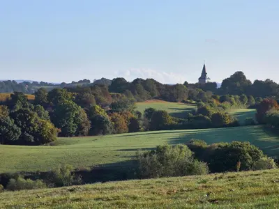 a green field with a church in the distance at Limbourg Nature Retreat in Hèvremont