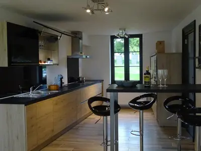 a kitchen with a black counter and some chairs at La Balade d'Annie in Trooz