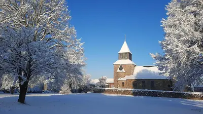 a church covered in snow with a tree in front at La Balade d'Annie in Trooz