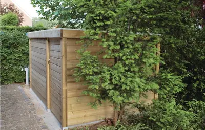 a wooden privacy fence with a tree next to it at Holiday Home Kinrooi I in Kinrooi
