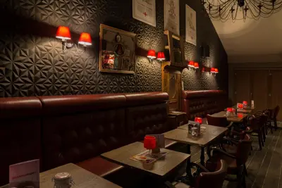 a restaurant with tables and benches and red lamps at de Twie Keuninge in Maasmechelen