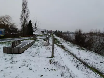 a snow covered field with benches and a fence at de Twie Keuninge in Maasmechelen