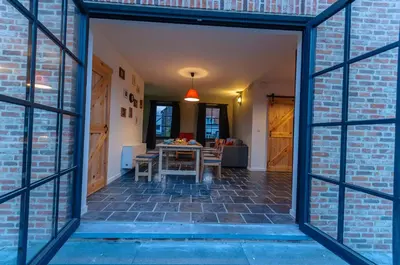 an open door leading to a dining room with a brick wall at Het Kloosterzicht in Borgloon