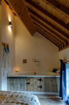 a bedroom with a tub in a room with wooden ceilings at Het Kloosterzicht in Borgloon
