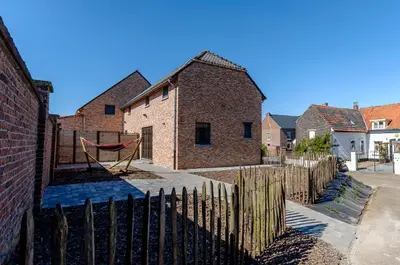a fence with a hammock in front of a house at Het Kloosterzicht in Borgloon