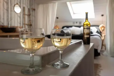 two glasses of white wine on a counter with a bottle of wine at Du Coté de chez Jeanne, Suite in Verviers