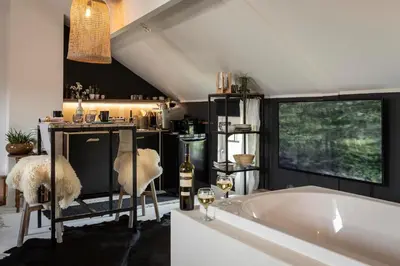a bathroom with a tub and two chairs and a window at Du Coté de chez Jeanne, Suite in Verviers