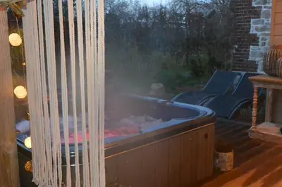 a hot tub on a deck with a grill at Du Coté de chez Jeanne, Suite in Verviers