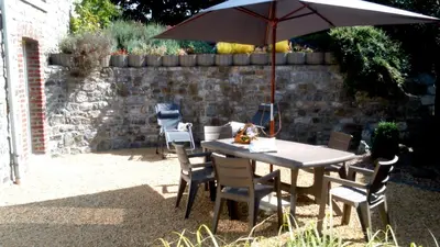 a table and chairs with an umbrella in a yard at Au Marronnier in Lontzen