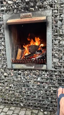 a fire in a brick fireplace with a person watching at Relax Trois Bornes - De Grenspost in Gemmenich