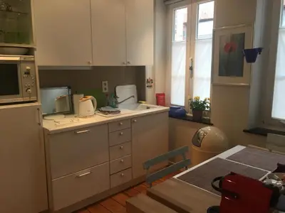 a kitchen with white cabinets and a sink and a table at Tongeren Schuttersgang 1 in Tongeren