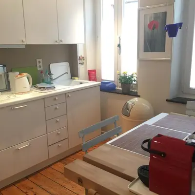 a kitchen with white cabinets and a table with a red suitcase at Tongeren Schuttersgang 1 in Tongeren
